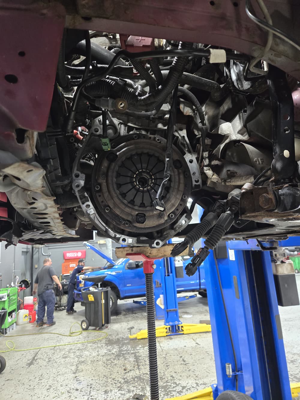 Clutch and flywheel exposed under a vehicle during a transmission job