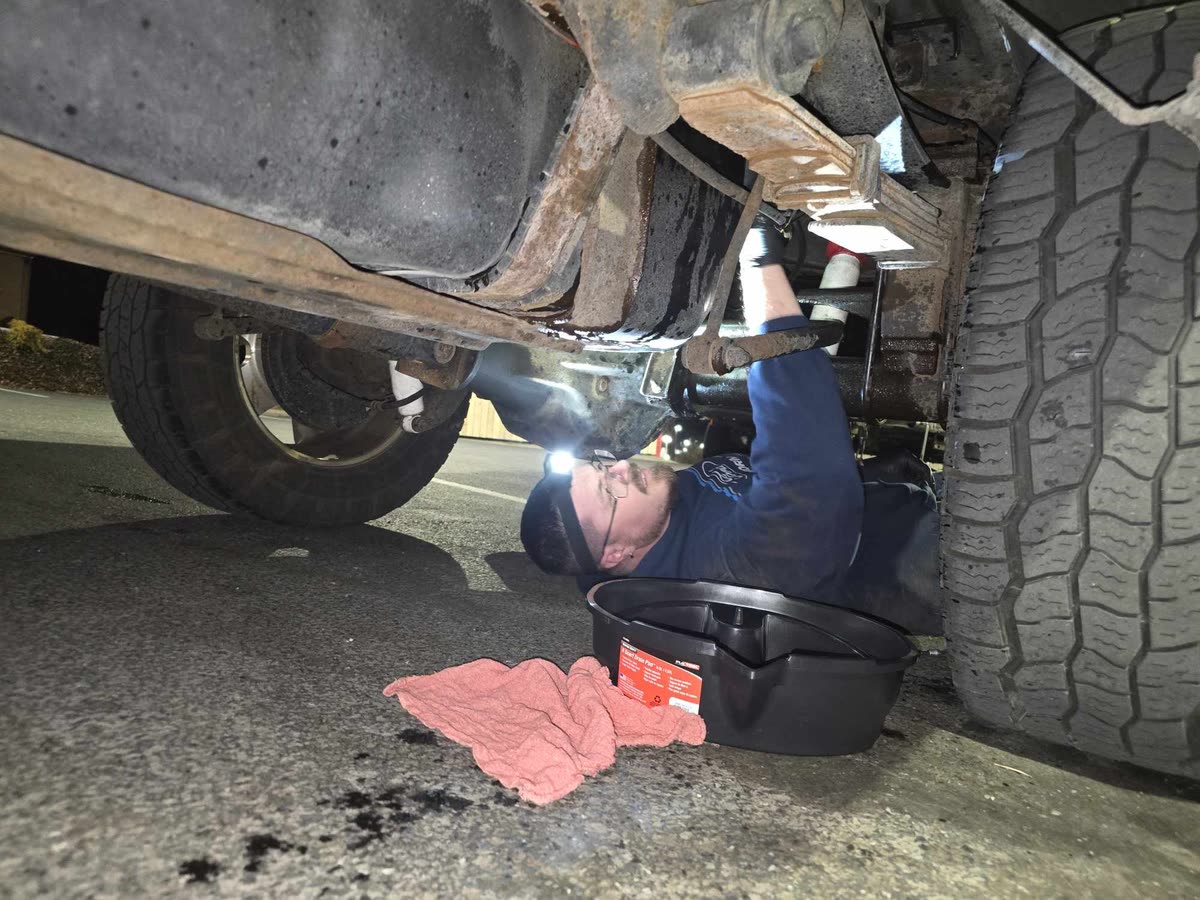 Justin working under a truck with a flashlight at Just Right Automotive
