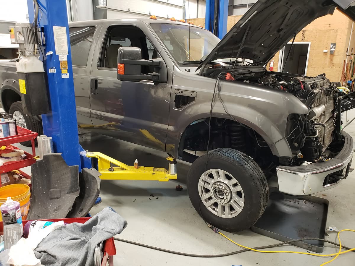 Work truck in the shop bay receiving front-end engine repair